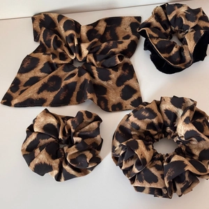 Detailed set of four leopard print scrunchies in various sizes and styles on white background