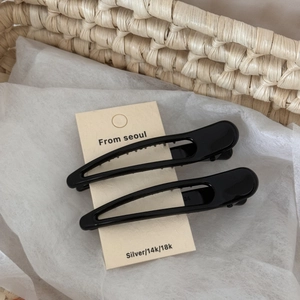 Detail of two black glossy duckbill hair clips displayed on a Korean style paper card