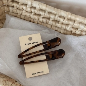 Detail of two dark brown tortoiseshell hair clips on a display card in a woven basket
