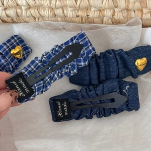 Detailed view of blue pleated fabric hair clips with gold heart charms and handmade labels