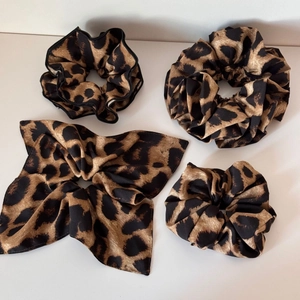Detail of four-piece leopard print scrunchie set featuring satin fabric and bow tie design