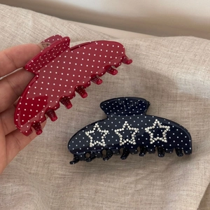 Détail de pinces à cheveux à pois rouges et bleu marine avec étoiles en strass