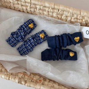 Detail of four blue fabric hair clips with gold heart charms in a rustic woven basket