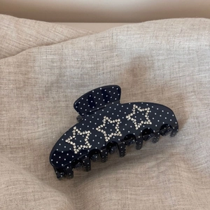 Détail d'une pince à cheveux bleu marine à pois avec trois étoiles en strass brillants