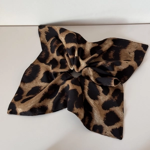 Detail of leopard print satin scrunchie with soft pleated texture and glossy finish