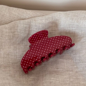 Vue détaillée de la grande pince à cheveux rouge à pois blancs sur fond en lin
