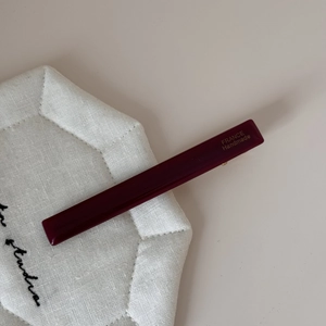 Détail d'une barrette en acétate rouge foncé avec inscription dorée faite à la main