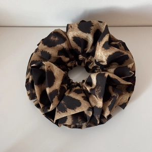 Close-up of large leopard print fabric scrunchie with soft texture and pleated design