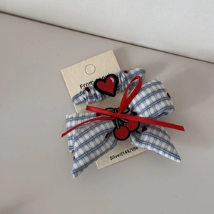 Dettaglio di un elastico per capelli a quadri blu con ricamo a cuore rosso