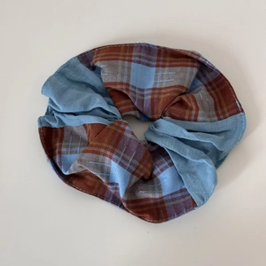 Gros plan détaillé d'un chouchou en tissu patchwork à carreaux rouge et bleu avec plis