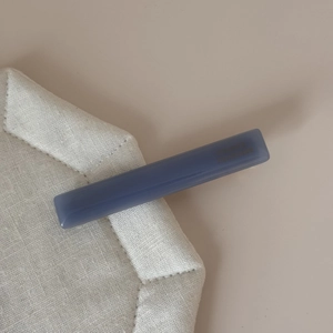 Détail de la pince à cheveux en acétate bleu-gris avec marquage doré sur tissu