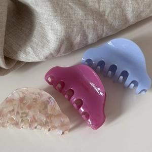 Trois pinces à cheveux en acétate marbré et unicolore sur un fond de tissu naturel