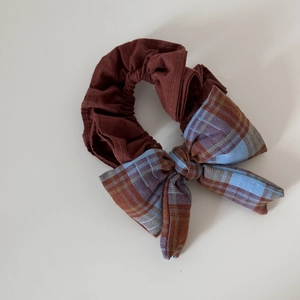 Détail du chouchou en tissu à carreaux rouge et bleu avec une grande décoration de nœud