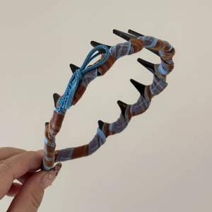 Détail d'un serre-tête à carreaux avec dents antidérapantes et nœud vintage bleu