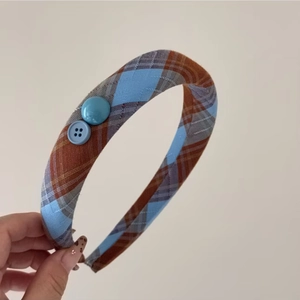 Détail du serre-tête à carreaux rouge et bleu avec boutons décoratifs et texture en tissu