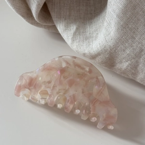 Détail de la pince à cheveux en acétate rose marbré sur un tissu en coton doux