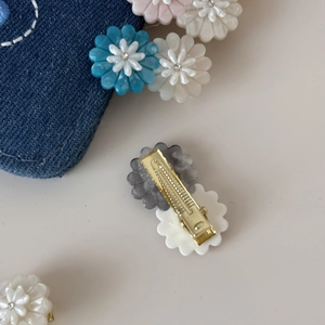 Detailed view of daisy acetate hair clips with crystal centers and golden metal grips