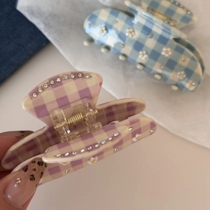 Dettaglio delle mollette per capelli in acetato a quadri con fiori e strass scintillanti