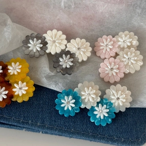 Macro shot of colorful acetate daisy hair clips with crystal centers on denim