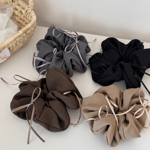 Détail de quatre chouchous style ballet avec rubans en gris, noir, marron et beige