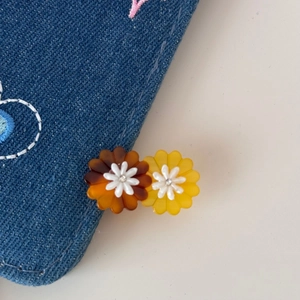 Close-up of vibrant daisy hair clips featuring brown and yellow gradient acetate petals