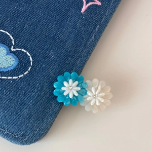 Detail of blue denim fabric with embroidered pink hearts and small floral 3D appliqués