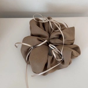Détail d'un chouchou en tissu côtelé marron orné d'élégants nœuds en ruban blanc