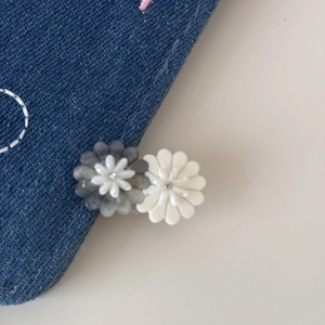 Close-up of grey and cream acetate daisy hair clips with crystals on blue denim