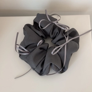 Détail d'un chouchou gris foncé en tissu côtelé avec nœud élégant et texture plissée