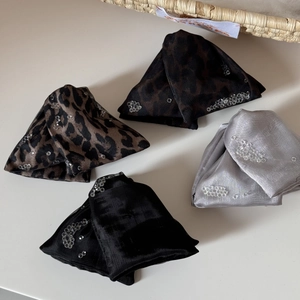 Detailed view of four leopard print and sequined fabric hair ties on a light background