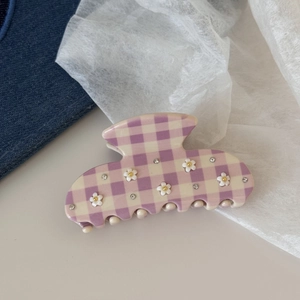 Dettaglio della molletta in acetato a quadretti viola con strass e decorazioni floreali