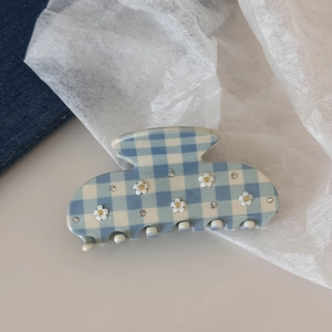 Dettaglio del fermaglio per capelli a scacchi blu con fiore bianco e strass lucidi