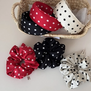 Detailed close-up of fluffy polka dot satin scrunchies and headbands on cream background