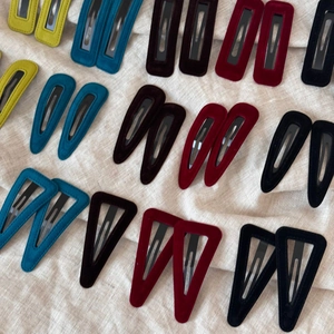 Detail of velvet textured hair clips in drop, rectangle, and triangle shapes on linen cloth