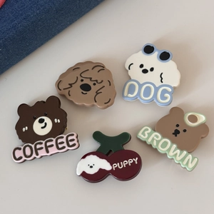 Détail de cinq pin's en émail mignons avec chiens et ours sur fond crème doux