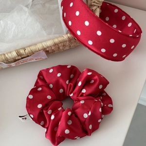 Macro shot of red satin scrunchie and headband with white polka dots and cherry tag