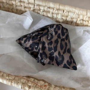 Close-up of leopard print hair claw clip with sparkling crystal beads in a woven basket