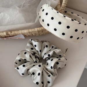 Close-up of fluffy polka dot satin scrunchie and wide headband set in elegant cream