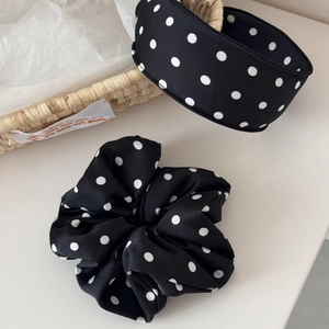 Close-up of black and white polka dot satin headband and scrunchie set on a table