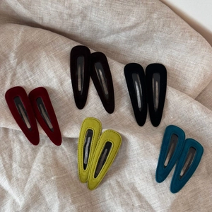 Detail of vintage velvet teardrop hair clips in multiple colors on linen fabric