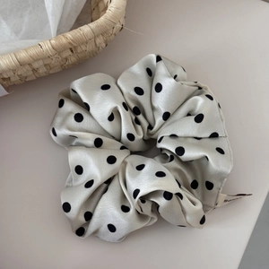 Close-up of fluffy polka dot satin hair scrunchie with silk texture and woven label