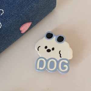 Détail d'une pince à cheveux petit chien blanc avec texte DOG bleu sur fond crème doux