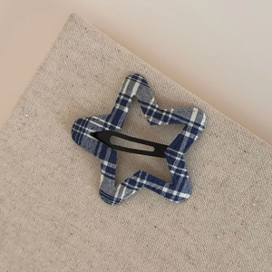 Detailed close-up of a star-shaped hair clip featuring blue and white plaid fabric texture