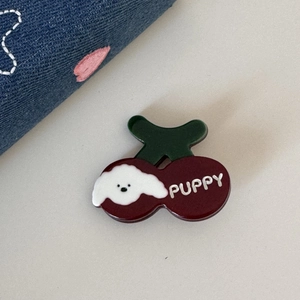Gros plan sur une pince à cheveux cerise avec motif chiot et texte PUPPY