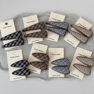 Detailed view of British plaid fabric hair clips in various geometric shapes and colors