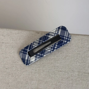 Detail showing blue and white plaid fabric texture on a vintage metal BB hair clip