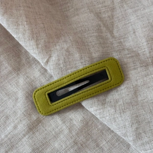 Detail of green velvet hair clip featuring stitching texture and black metal clasp