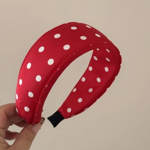 Close-up of a red padded headband with white polka dots and comfortable black fabric ends