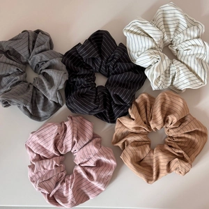 Cinq chouchous à rayures en gris noir beige rose et marron sur un fond beige épuré