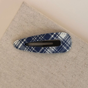 Detailed macro view of the blue and white plaid fabric texture on a teardrop BB hair clip